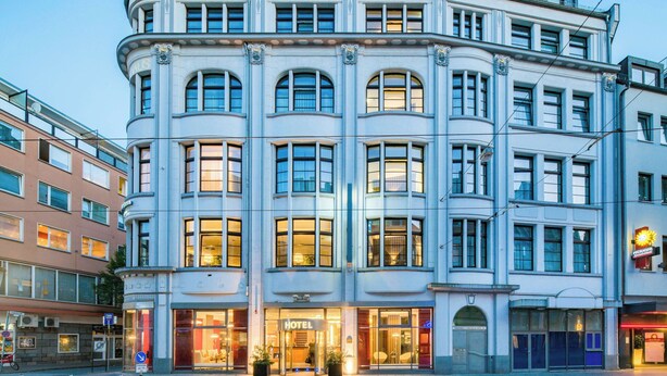 A corner building with a hotel entrance, large windows, and a classic architectural style.