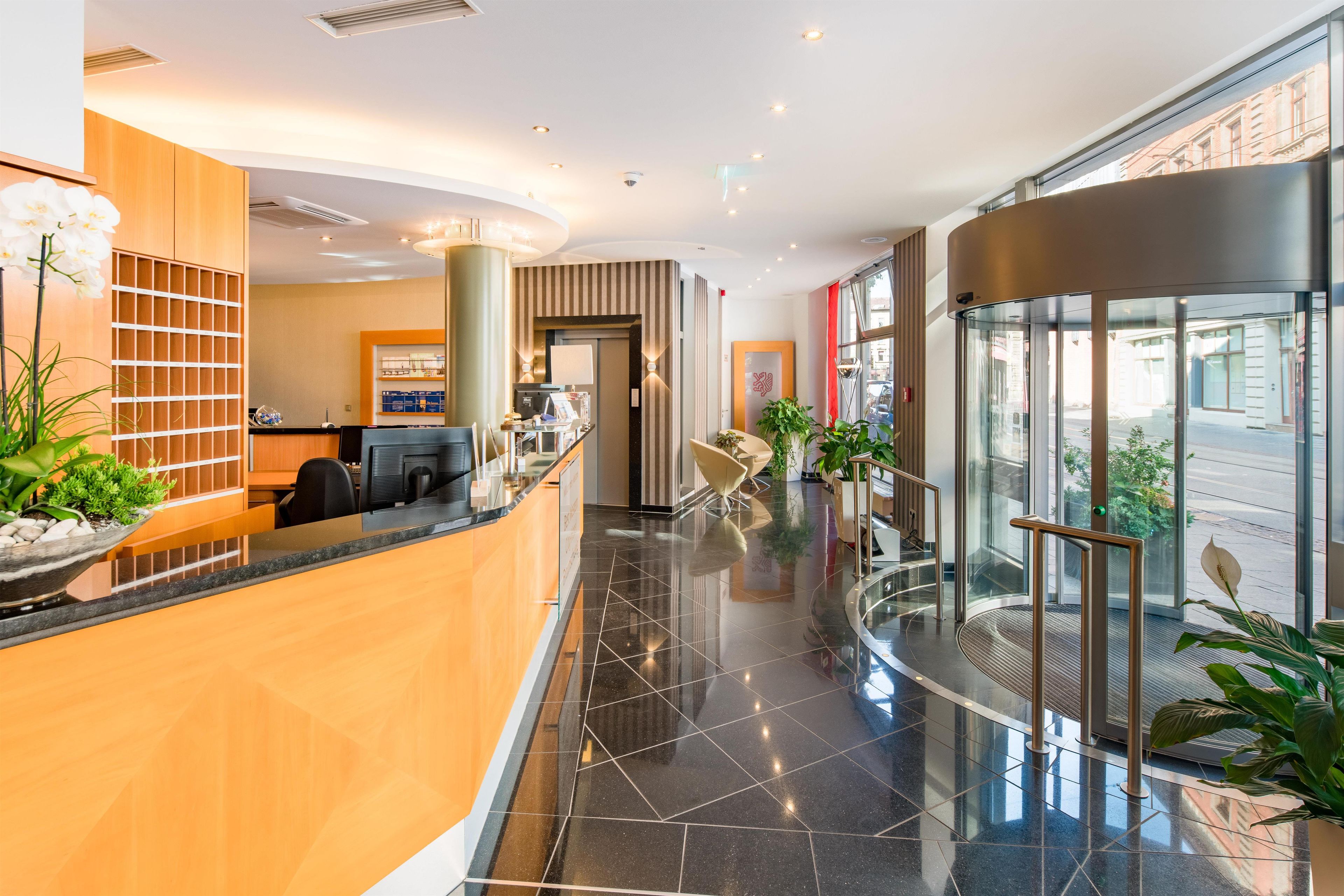 Eine moderne Hotelhalle mit einer Rezeption, einer Sitzecke und einem Glaselevator.