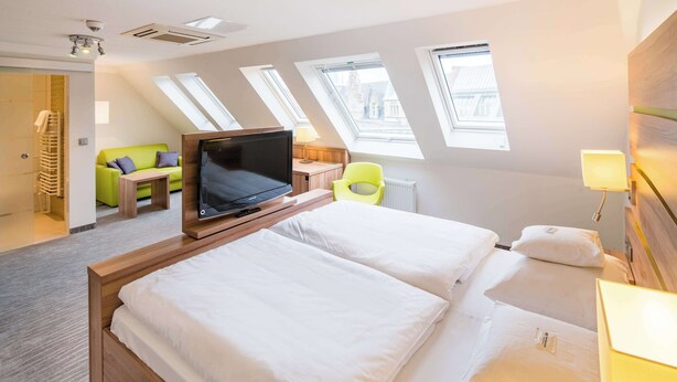 A hotel room with two beds, a TV, a green sofa, and skylights. - Best Western City-Hotel Braunschweig (Braunschweig)