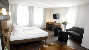 A hotel room with a bed, a desk, a sofa, and a TV. - Hotel Westerkamp (Osnabrueck)
