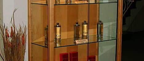 A glass display cabinet with various bottles and containers, likely for perfumes or spirits, in a well-lit room.