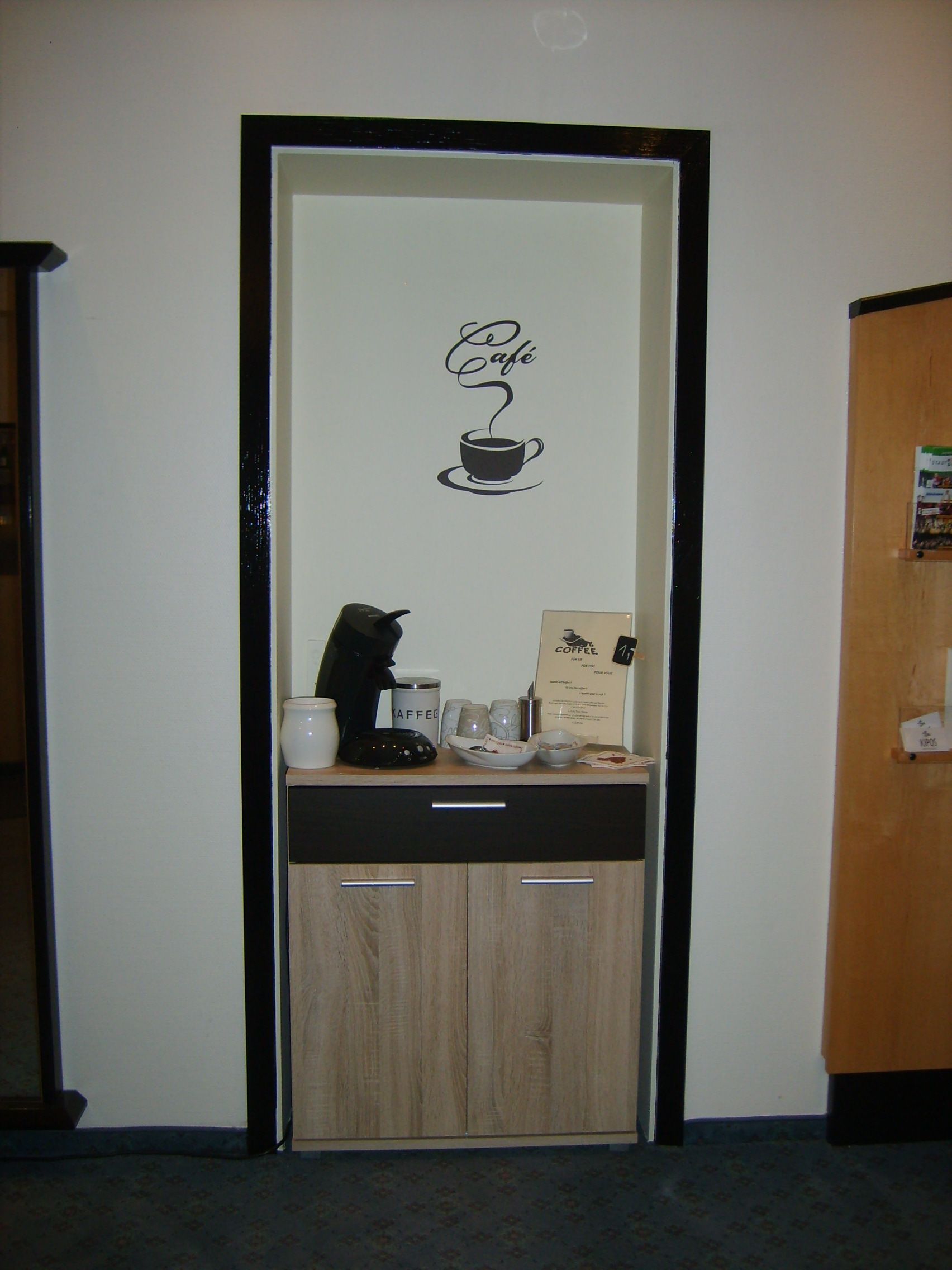 A door with a coffee-themed sign, a coffee maker, and a coffee service cart.