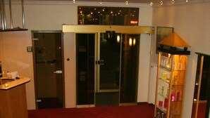 A hotel lobby with a red carpet, a reception desk, and a glass display case with items. - City Hotel by Celina (Hagen)