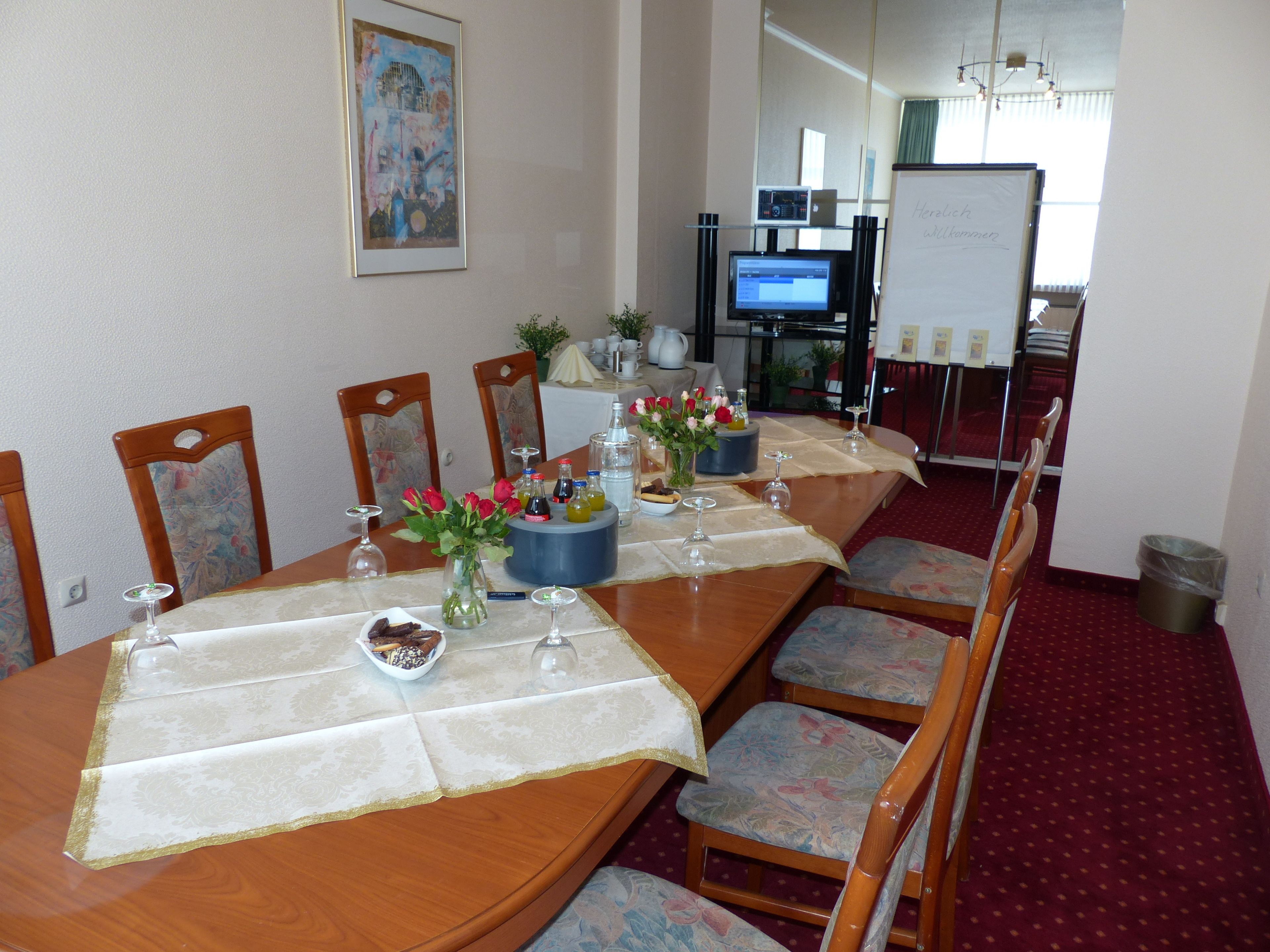 A conference room with a long table set for a meeting, equipped with chairs, a projector, and a whiteboard.