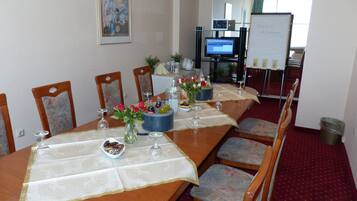 A conference room with a long table set for a meeting, equipped with chairs, a projector, and a whiteboard.