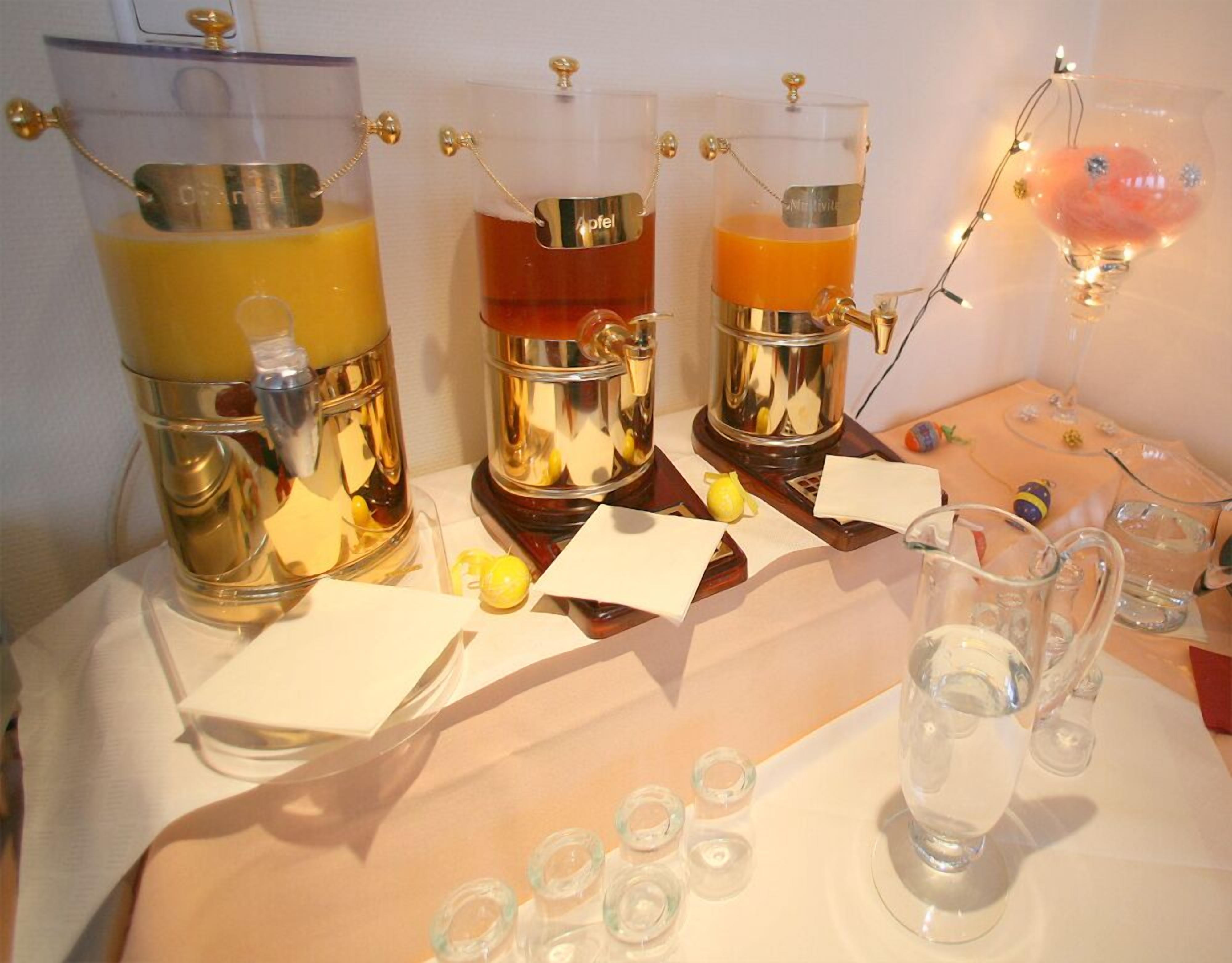 Une table avec trois distributeurs de boissons en métal, un pichet en verre et un verre contenant une substance rose.