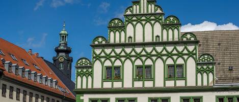 A building with a green and white facade, a clock tower, and a sign for tourist information.