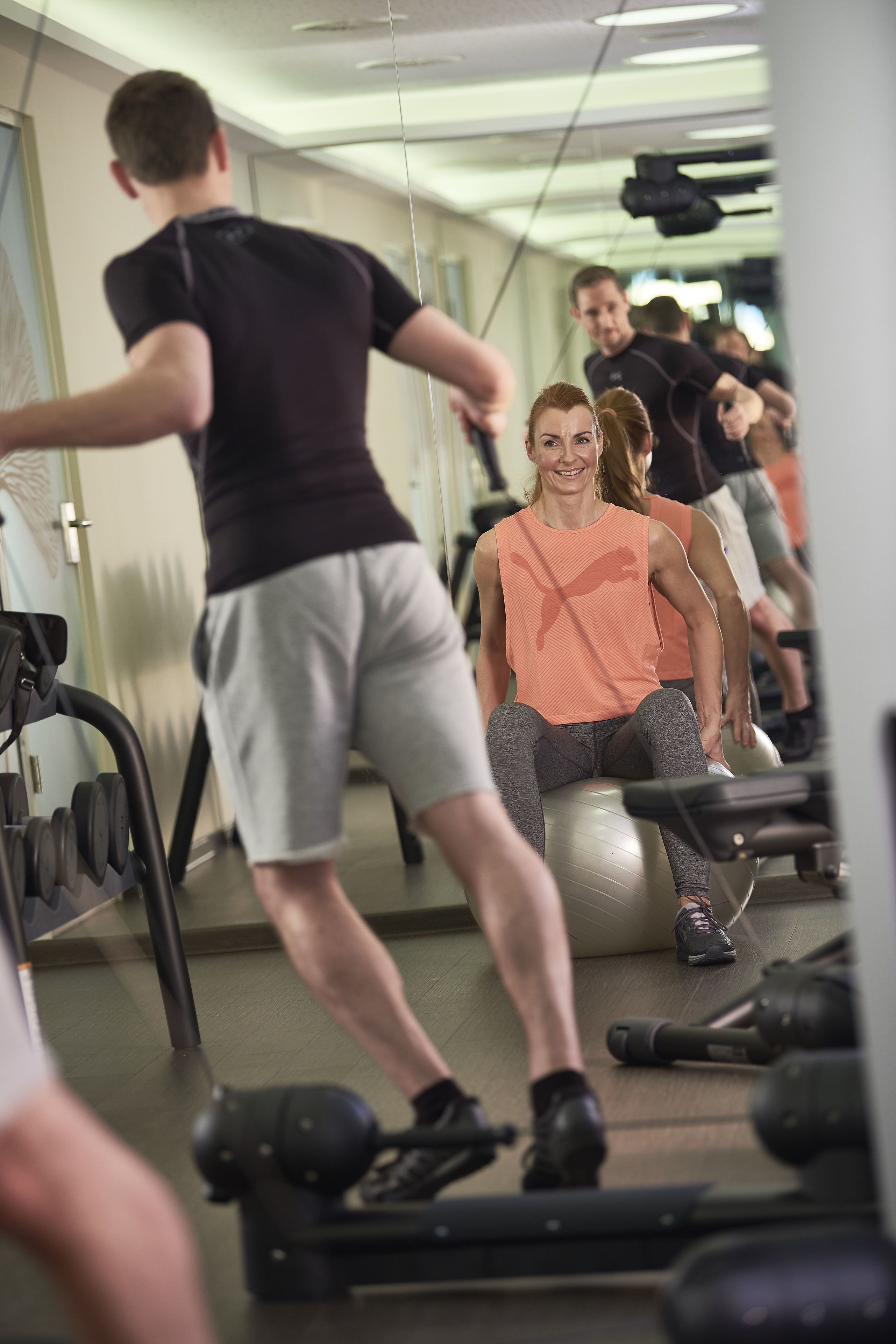 Un gimnasio con equipo de ejercicio y gente entrenando.