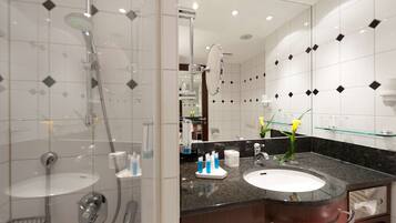 A modern bathroom with a glass shower enclosure, a sink with a marble countertop, and a large mirror.