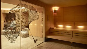 Un spa moderno con un separador de vidrio, una banca de madera y una lámpara fijada a la pared.