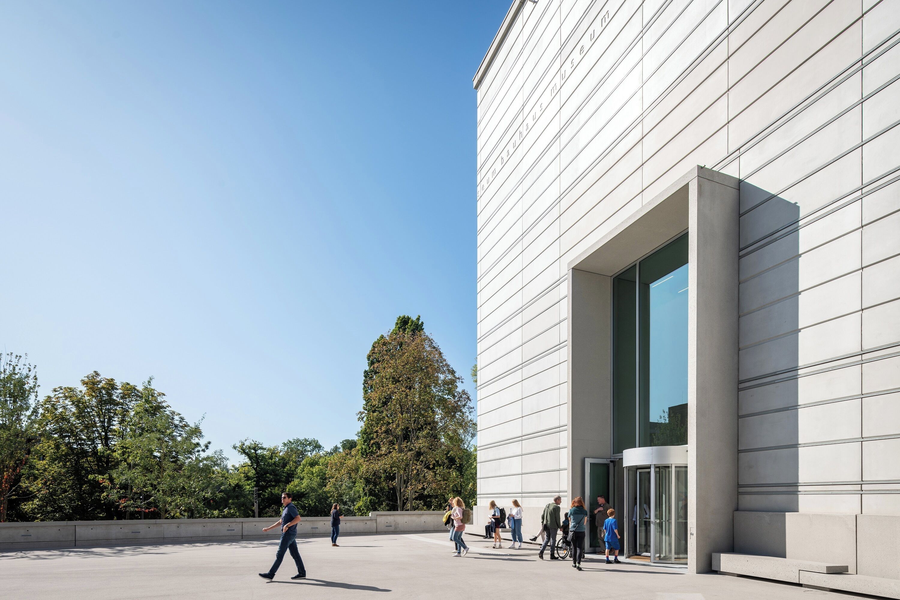A modern building with a large glass entrance and a clear sky.