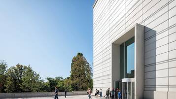 A modern building with a large glass entrance and a clear sky.