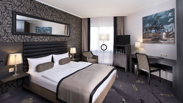 Une chambre d’hôtel avec un grand lit, un bureau, une télévision et une chaise.
