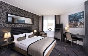 A hotel room with a large bed, a desk, a TV, and a chair. - Park Hotel am Berliner Tor (Hamburg)