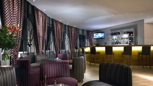 Un espace bar moderne, doté d’un téléviseur, de tabourets et d’une variété de bouteilles d’alcool.