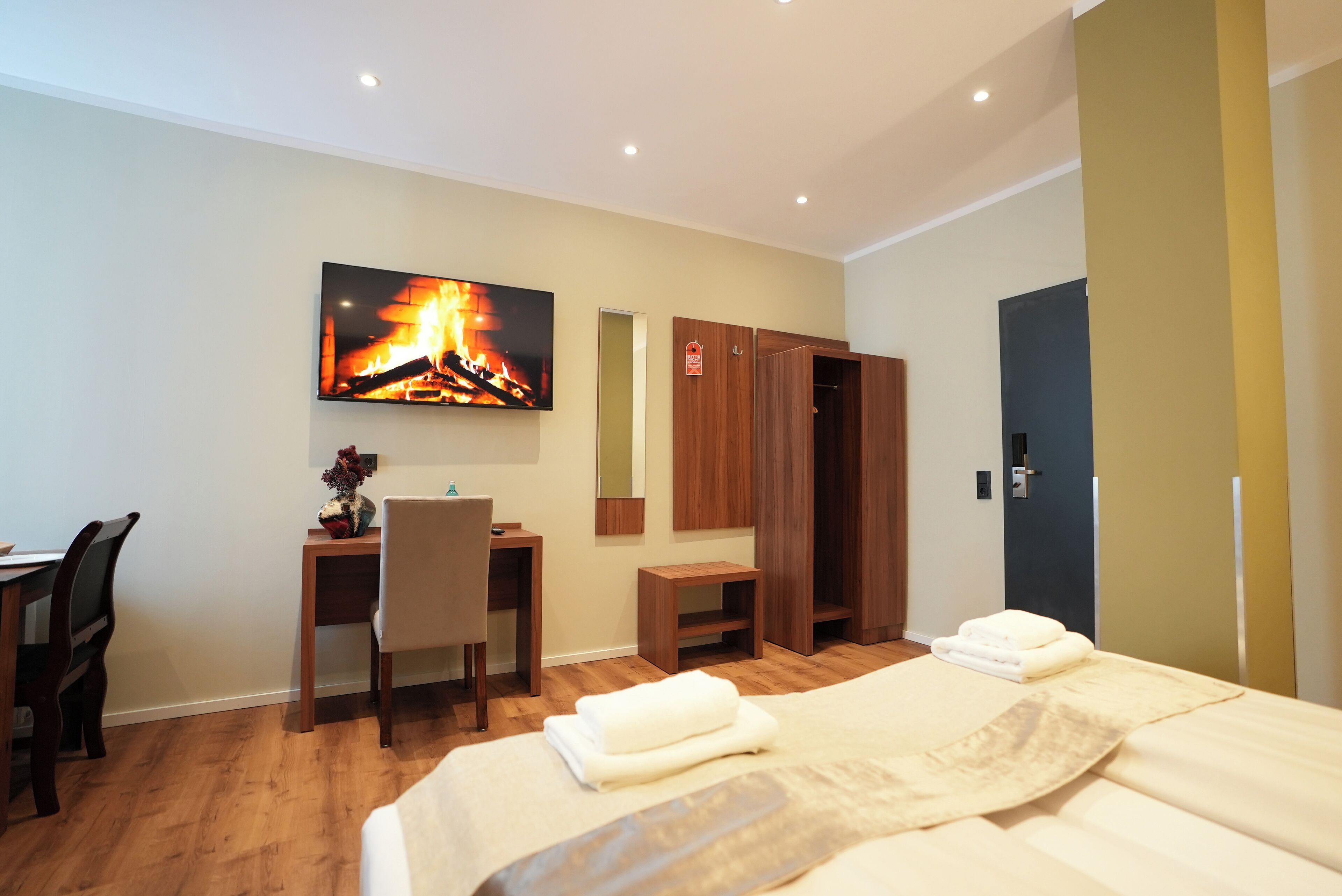 Une chambre d’hôtel équipée d’un lit, d’un bureau, d’une chaise, d’un téléviseur fixé au mur et d’une armoire.