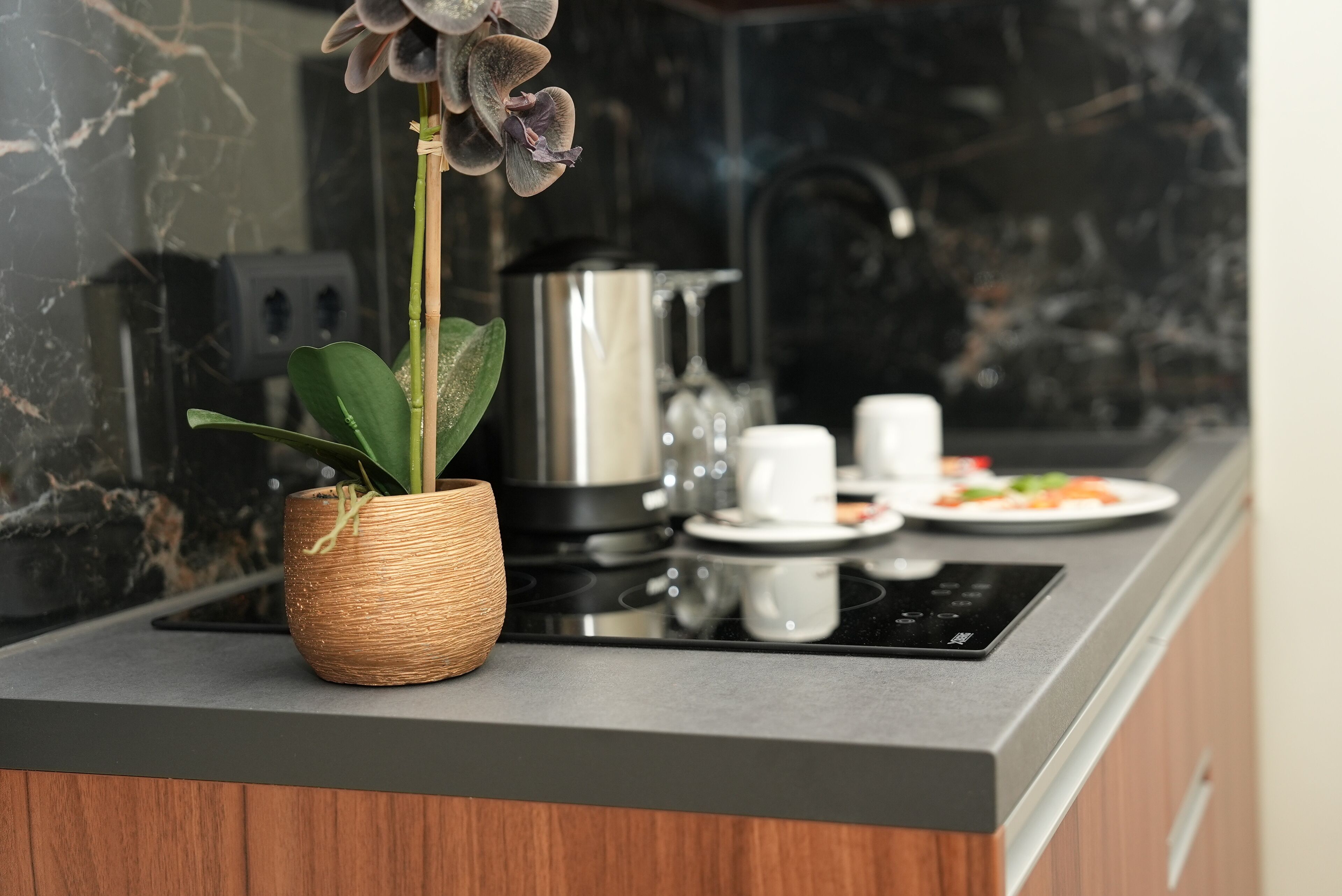 Eine moderne Küche mit Marmorfliesenspiegel, einem gewebten Blumentopf, einem Herd und einem Essbereich mit einem Teller Essen und einer Tasse.