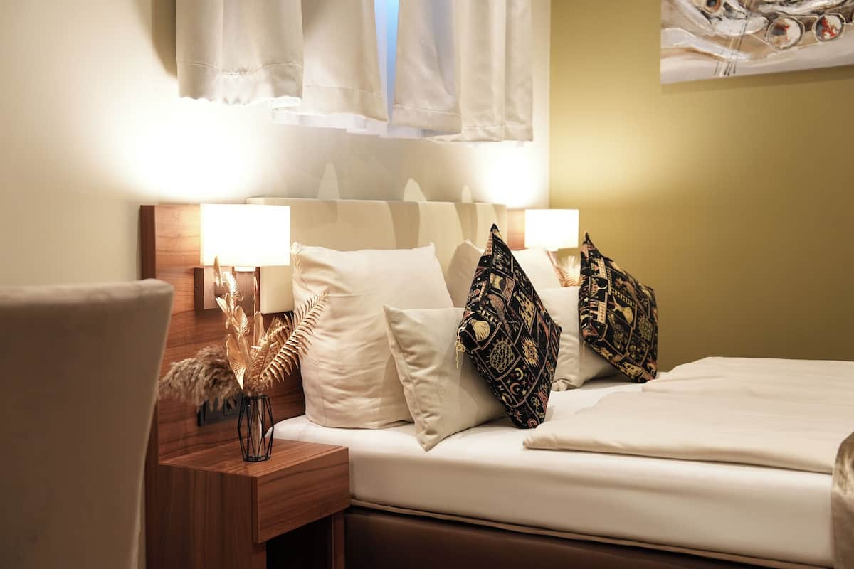 A neatly made bed with white linens, two bedside lamps, and decorative pillows.