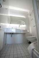 Un bagno con lavandino, specchio e servizi igienici bianchi.