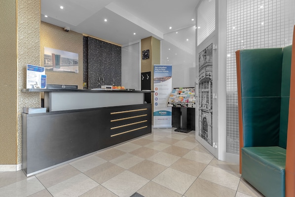 A reception area with a modern desk, a clock, and a poster.