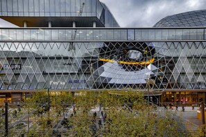 Un edificio moderno con fachada de vidrio geométrica y un amplio tragaluz circular.