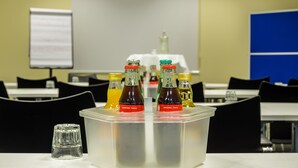 A conference room with a table holding a plastic container with bottles labeled "Original Taste." - Hotel Gertrudenhof (Cologne)