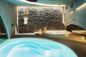 A modern bathroom with a stone wall, a bathtub, and a shower area.