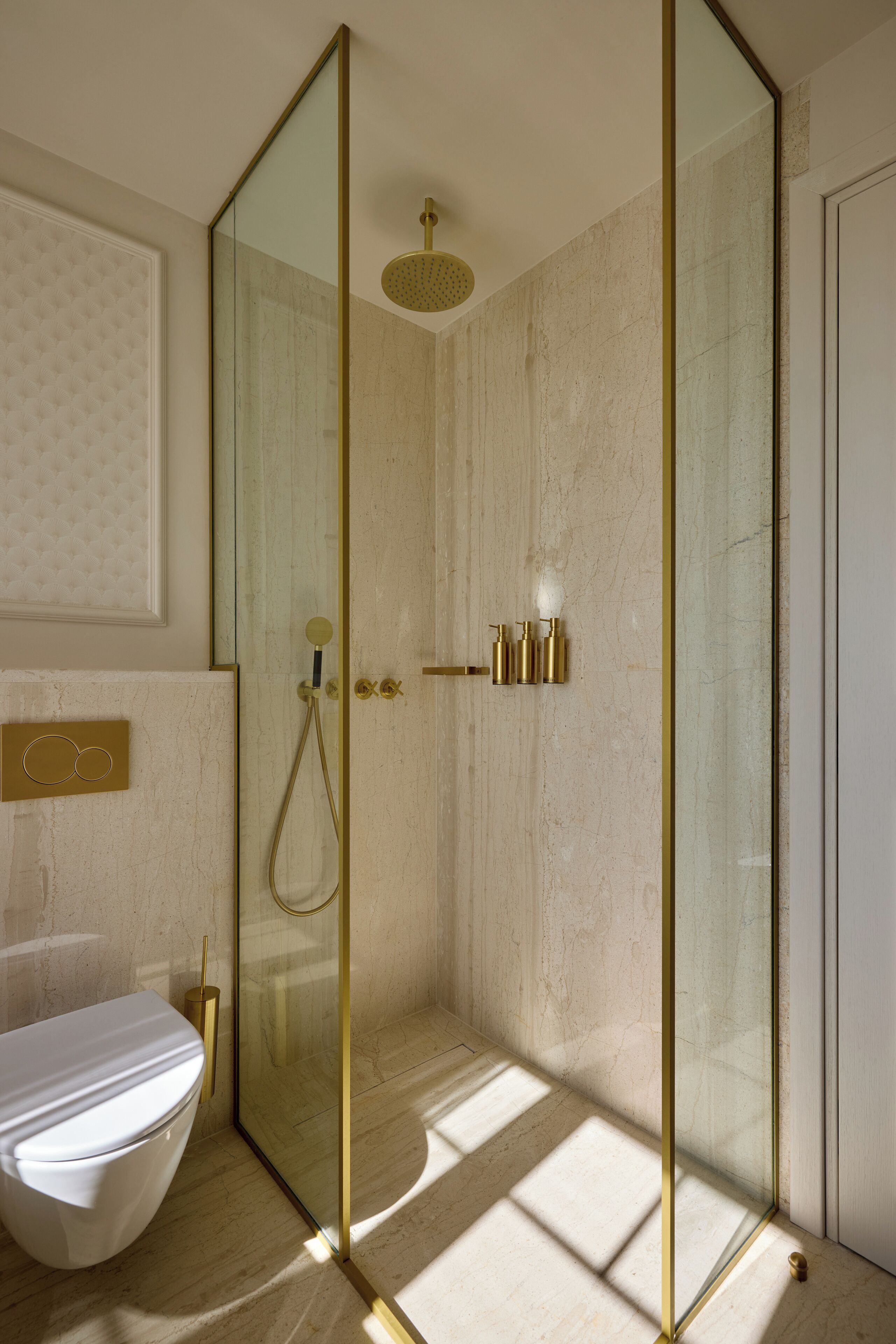 Un baño moderno con ducha de vidrio, inodoro blanco y suelo de mármol.