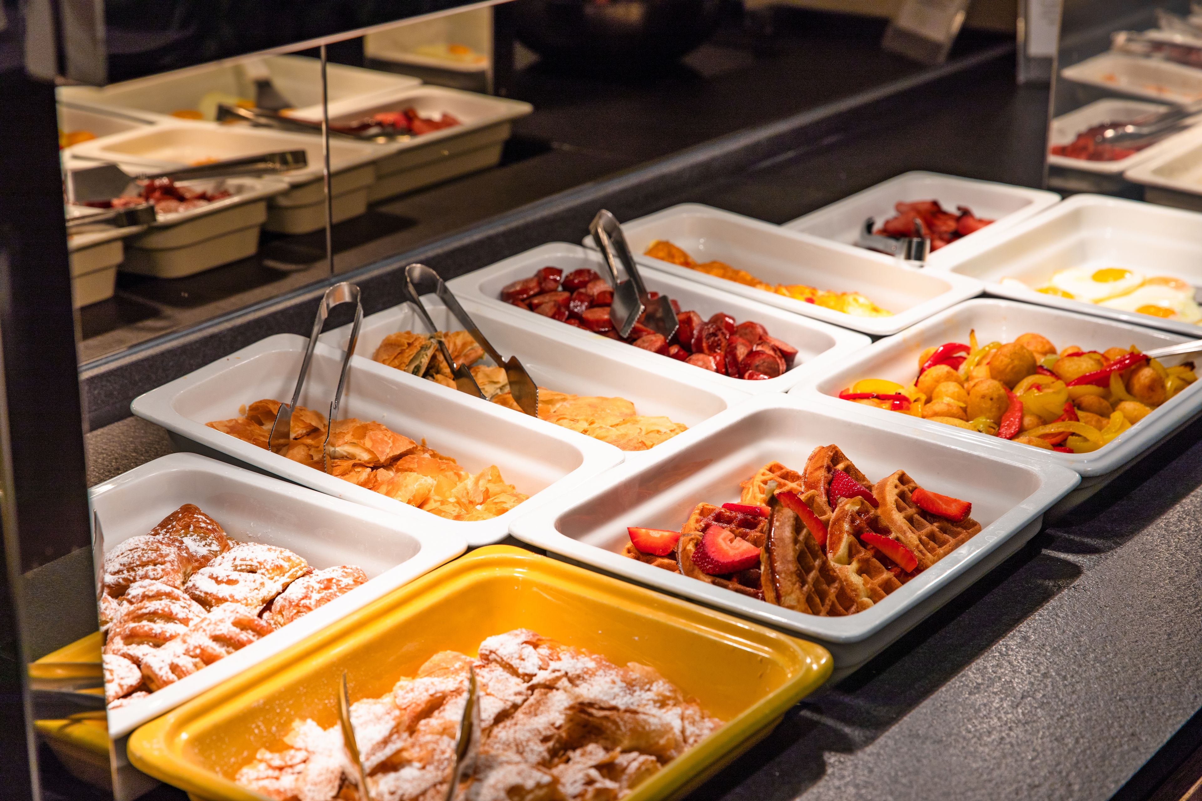 Un bufé con diversas opciones de comida, como gofres, frutas y pasteles.