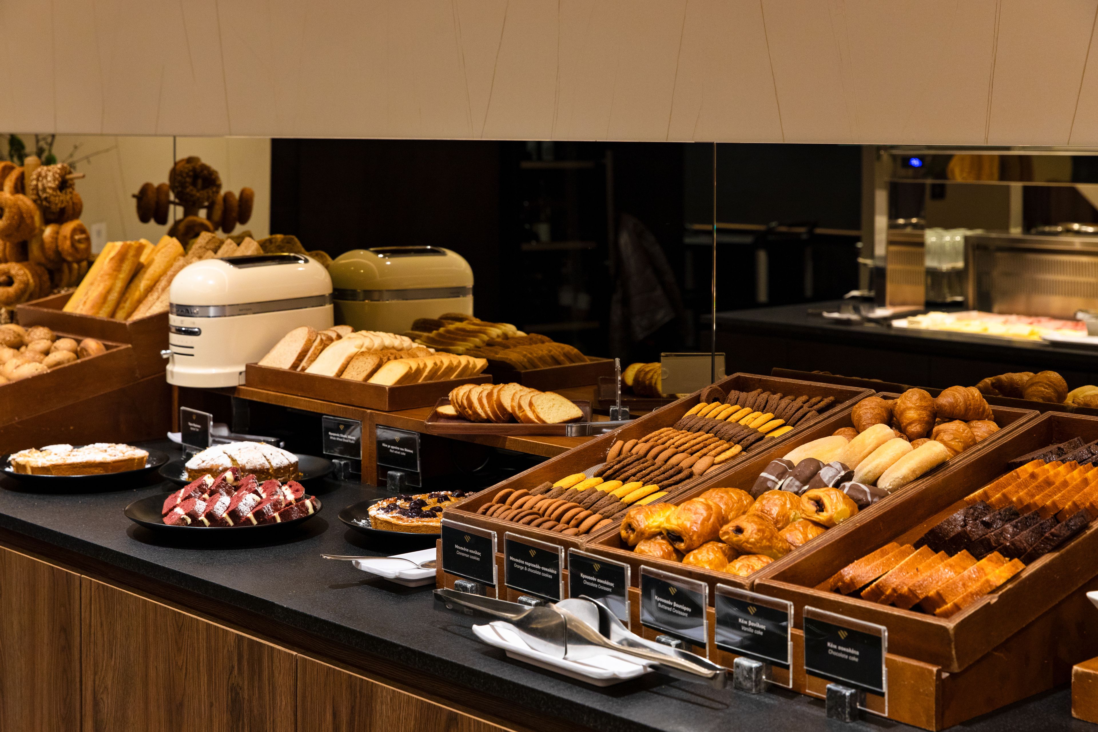 A breakfast buffet with various pastries, bread, and desserts.