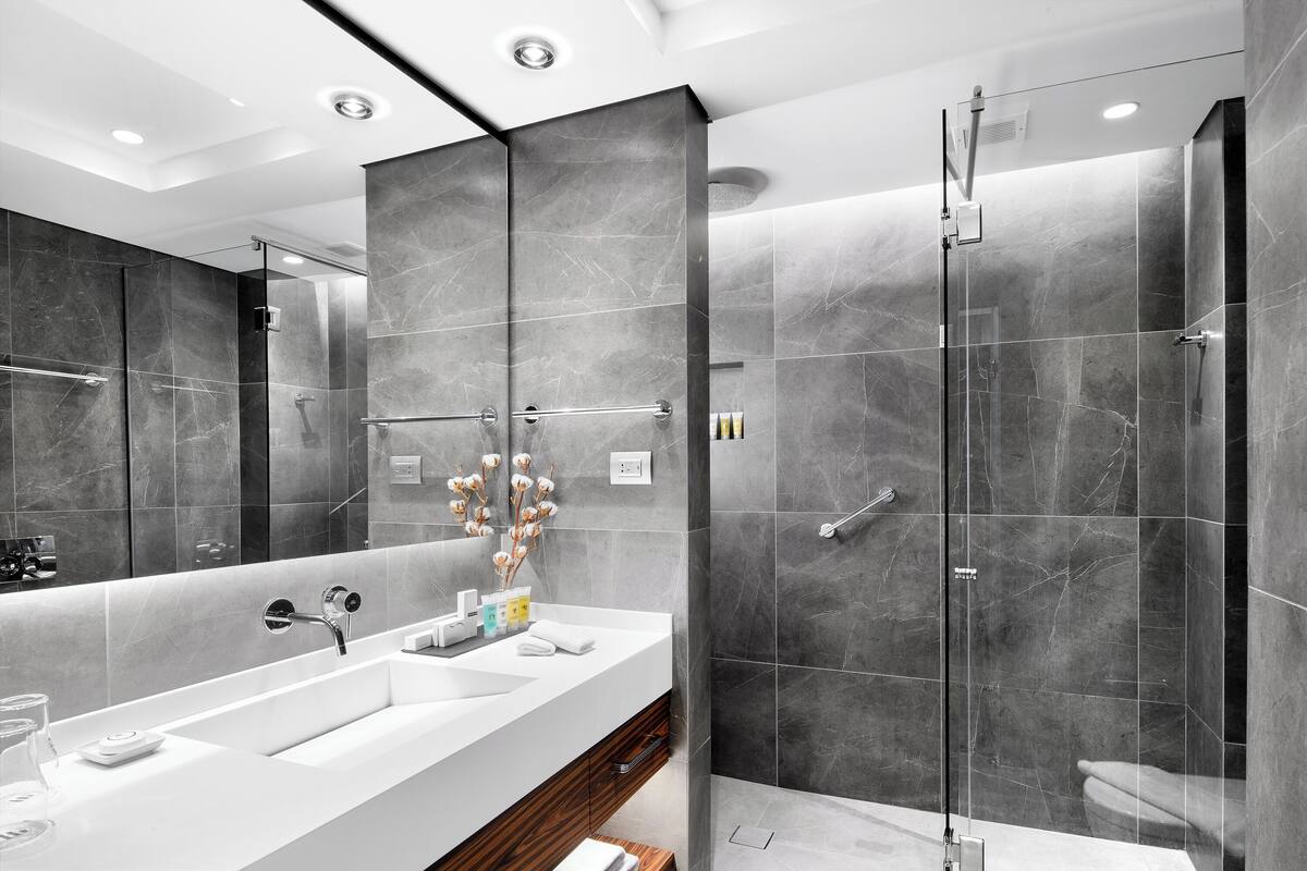 Casa de banho moderna com um espelho grande, duas pias, chuveiro e zona de duche envidraçada.