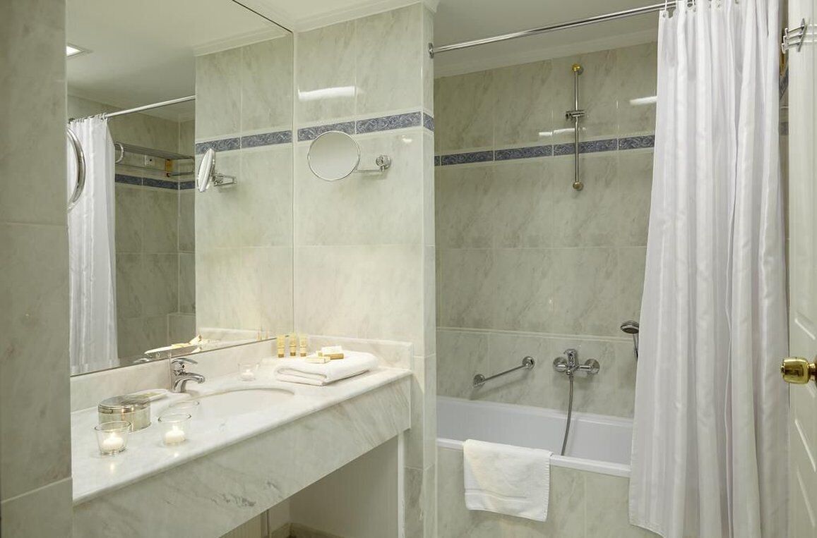 A modern bathroom with a marble sink, a bathtub, and a shower.