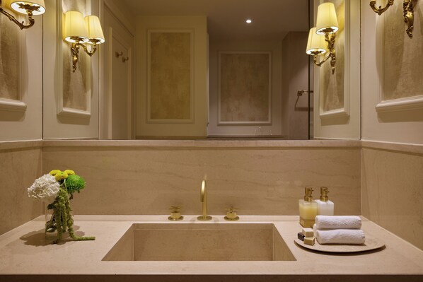 A bathroom with a sink, mirror, and wall sconces.