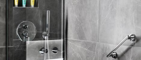 Un baño moderno con ducha acristalada, grifo cromado y barra de apoyo.