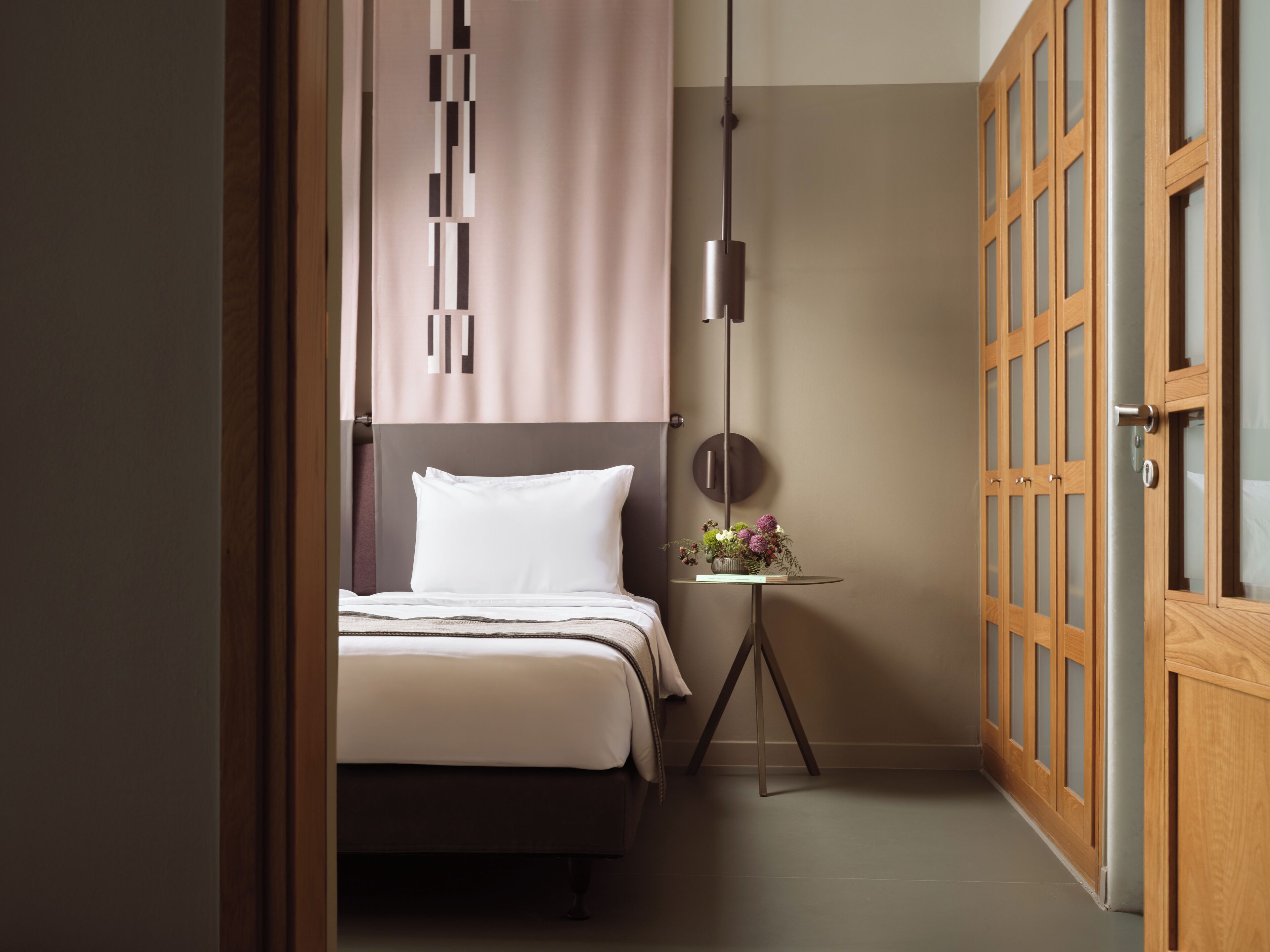 Un dormitorio moderno con cama, mesita de noche y lámpara de pared.