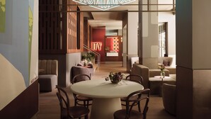Un moderno vestíbulo de hotel con una mesa de comedor redonda, varias sillas, una recepción y un letrero de neón.