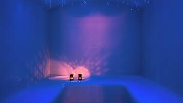 A room with a blue grid floor, two small tables, and hanging lights.