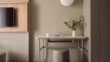Een moderne slaapkamer met een bed, een nachtkastje met een boek, een beker en een vaas met planten.