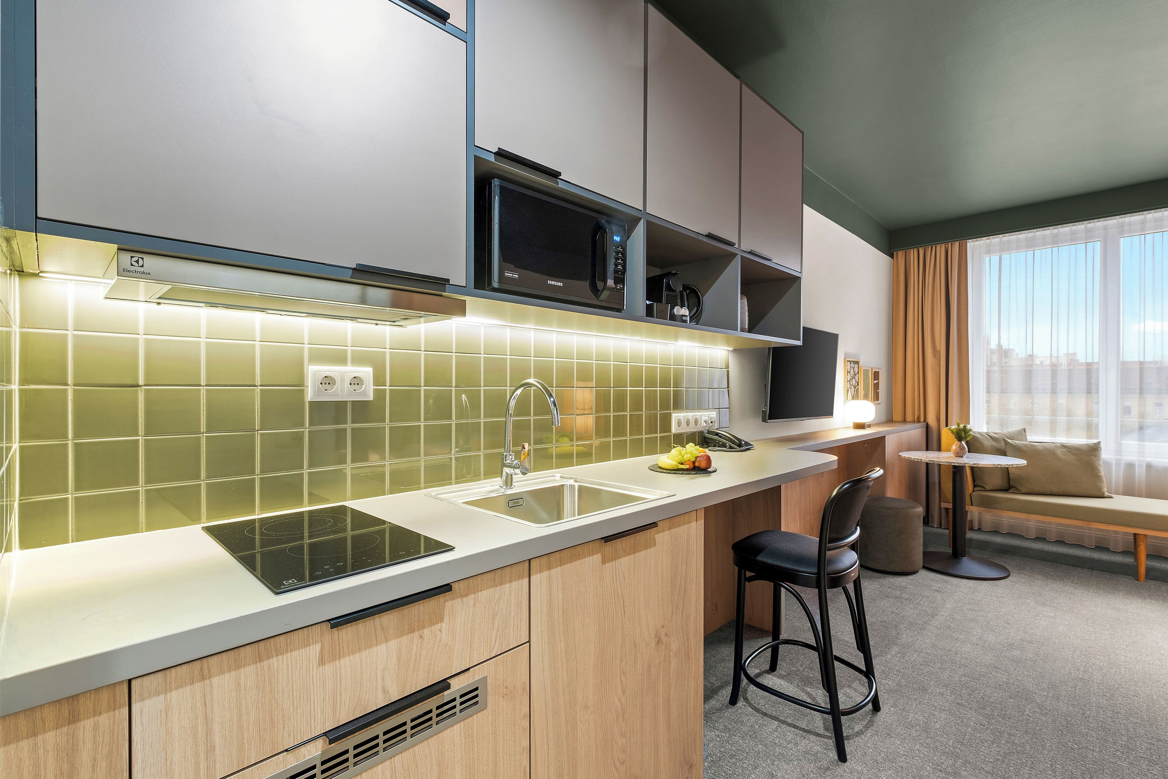 A modern kitchen with a built-in microwave, a sink, and a bar area with stools.