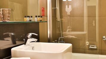 A modern bathroom with a glass shower enclosure, a white sink, and a bathtub.
