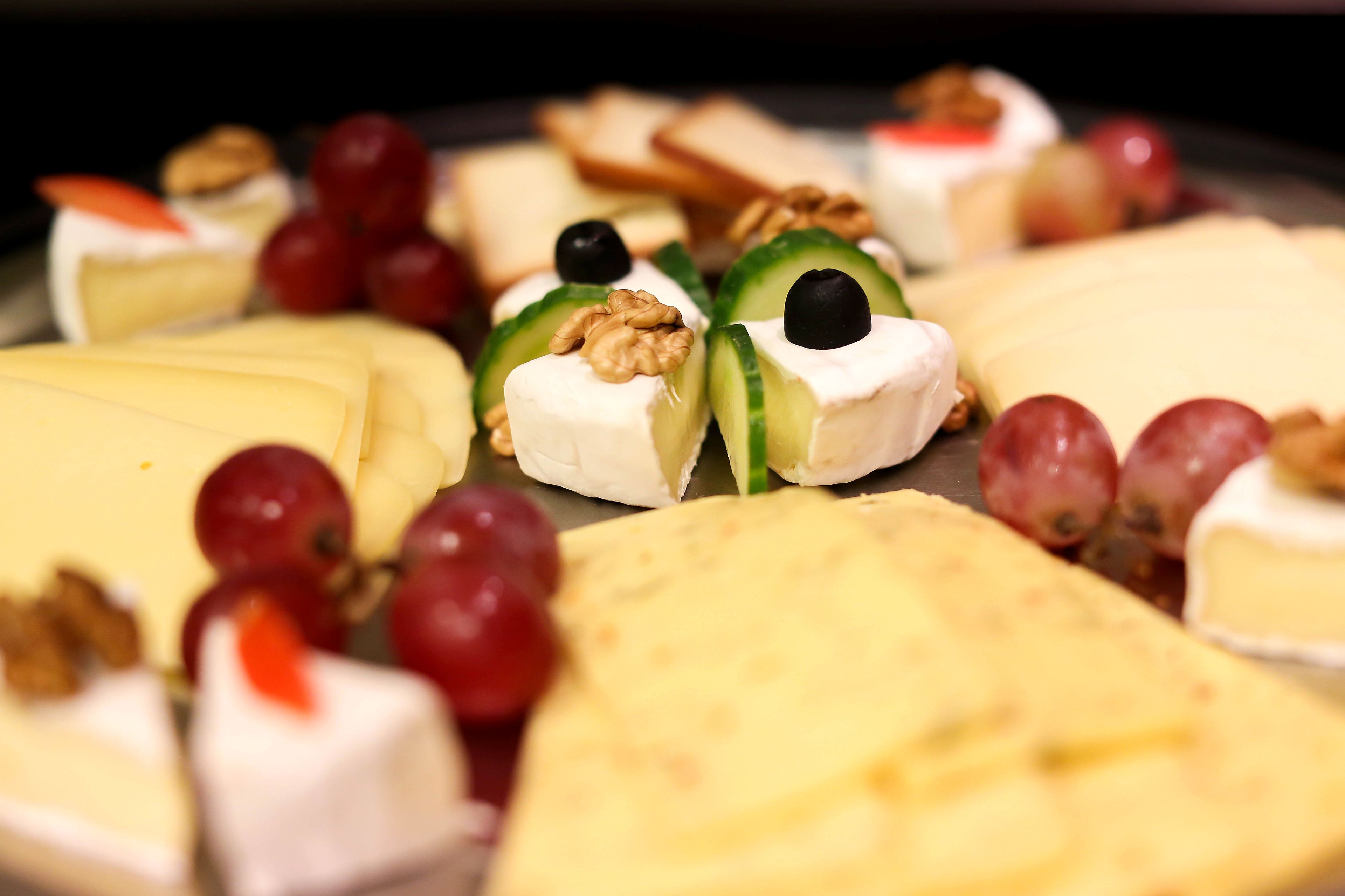 A variety of cheeses and fruits on a platter.