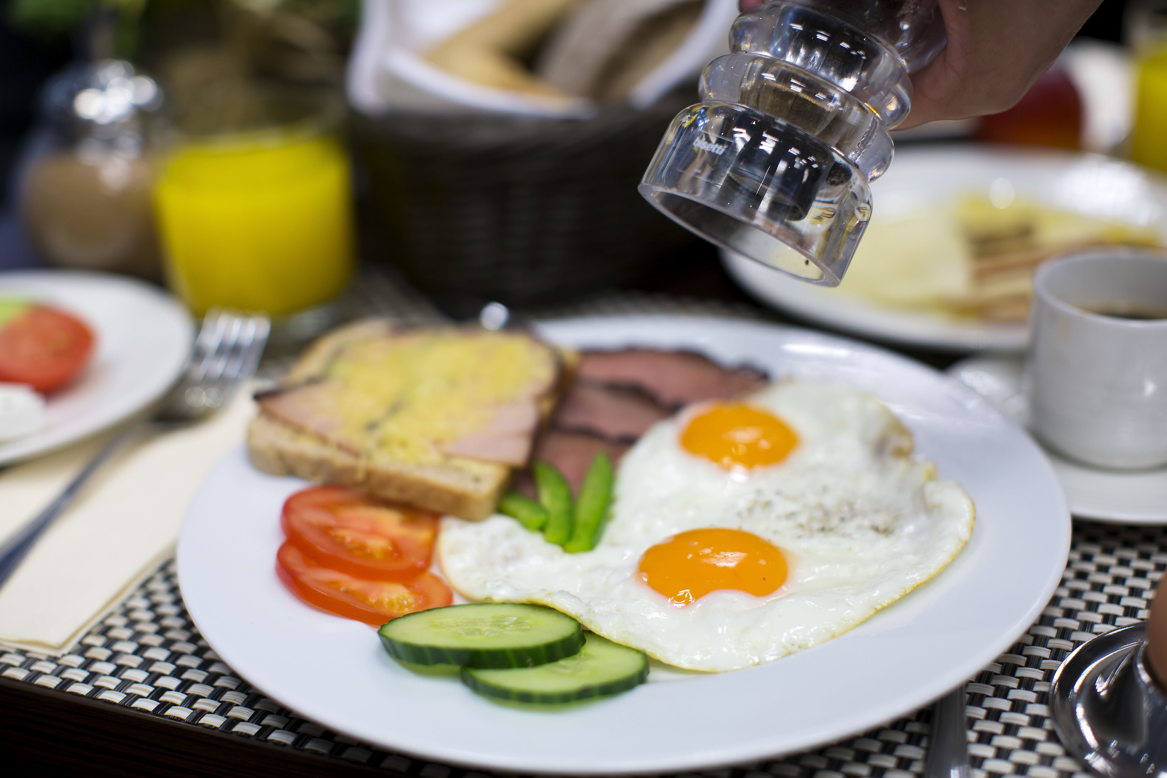 En frukosttallrik med ägg, tomater, gurka och rostat bröd.