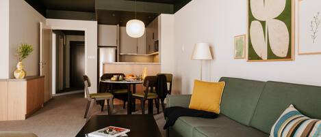 Una sala de estar moderna con un sofá verde, una mesa de centro y un comedor con sillas.