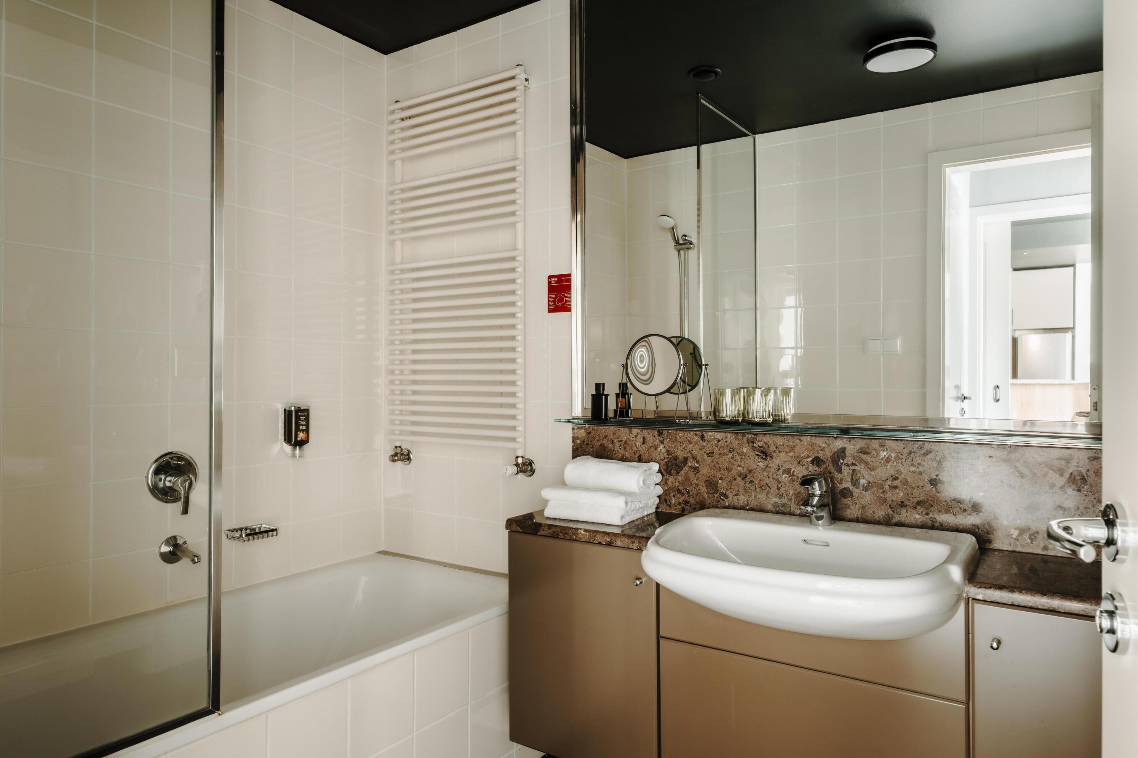 Un bagno moderno con cabina doccia in vetro, una vasca freestanding, un mobile lavabo e uno specchio grande.
