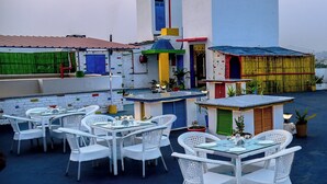 A rooftop patio with white wicker furniture and a small bar area. - ECKO Premier Vishnupriya (Udaipur)