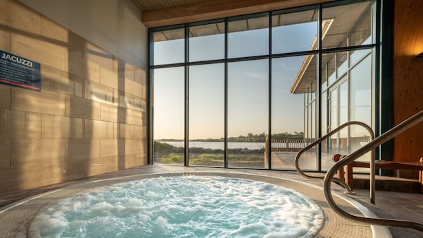 Un jacuzzi con vista a un cuerpo de agua a través de amplios ventanales.