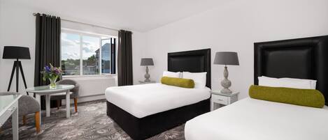Ein Hotelzimmer mit zwei Betten, einem Schreibtisch und einem Fenster mit Vorhängen.