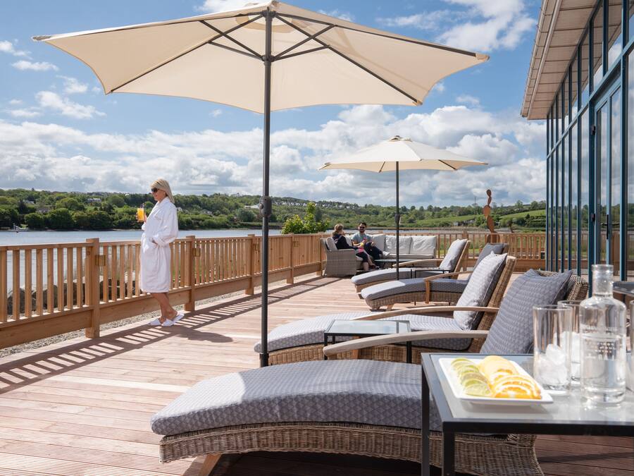 Terraza con mobiliario exterior, sombrillas y una mesa con bebidas y una bandeja de frutas.