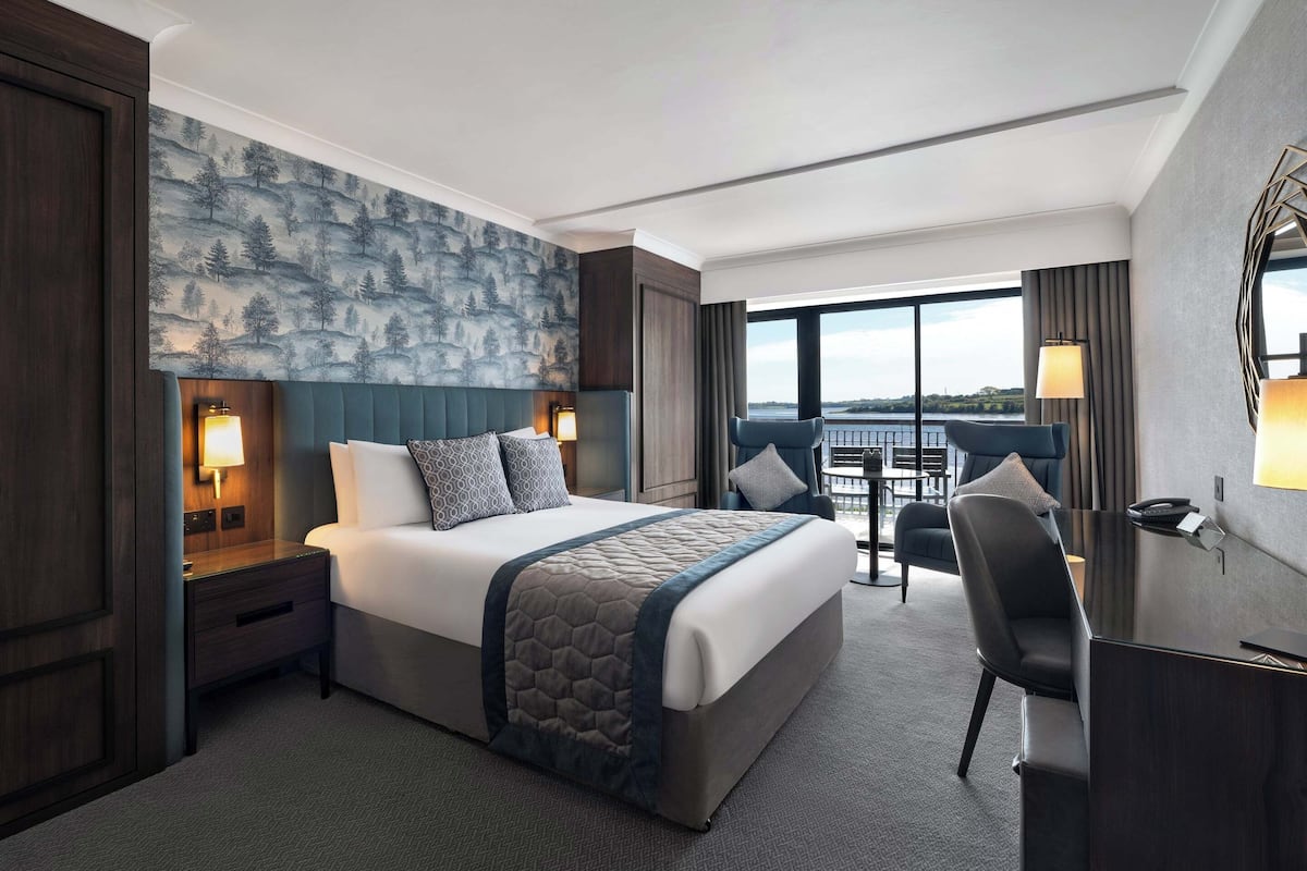 A hotel room with a large bed, a desk, and a view of the city.