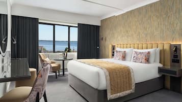 Een moderne hotelkamer met een groot bed, een bureau en uitzicht op zee.